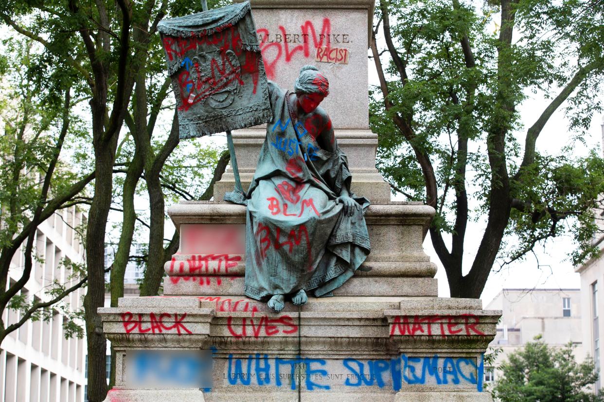 The bronze sculpture representing the Goddess of Masonry on the base of the statue of  Confederate general Albert Pike is seen with red paint after protestors toppled Pike's statue and set it on fire early Saturday, June 20, 2020, in Washington, D.C.