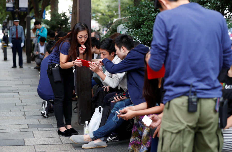 Customers sit in queue for the release of Apple’s new iPhone 8 and 8 Plus outside the Apple Store in Tokyo’s Omotesando shopping district