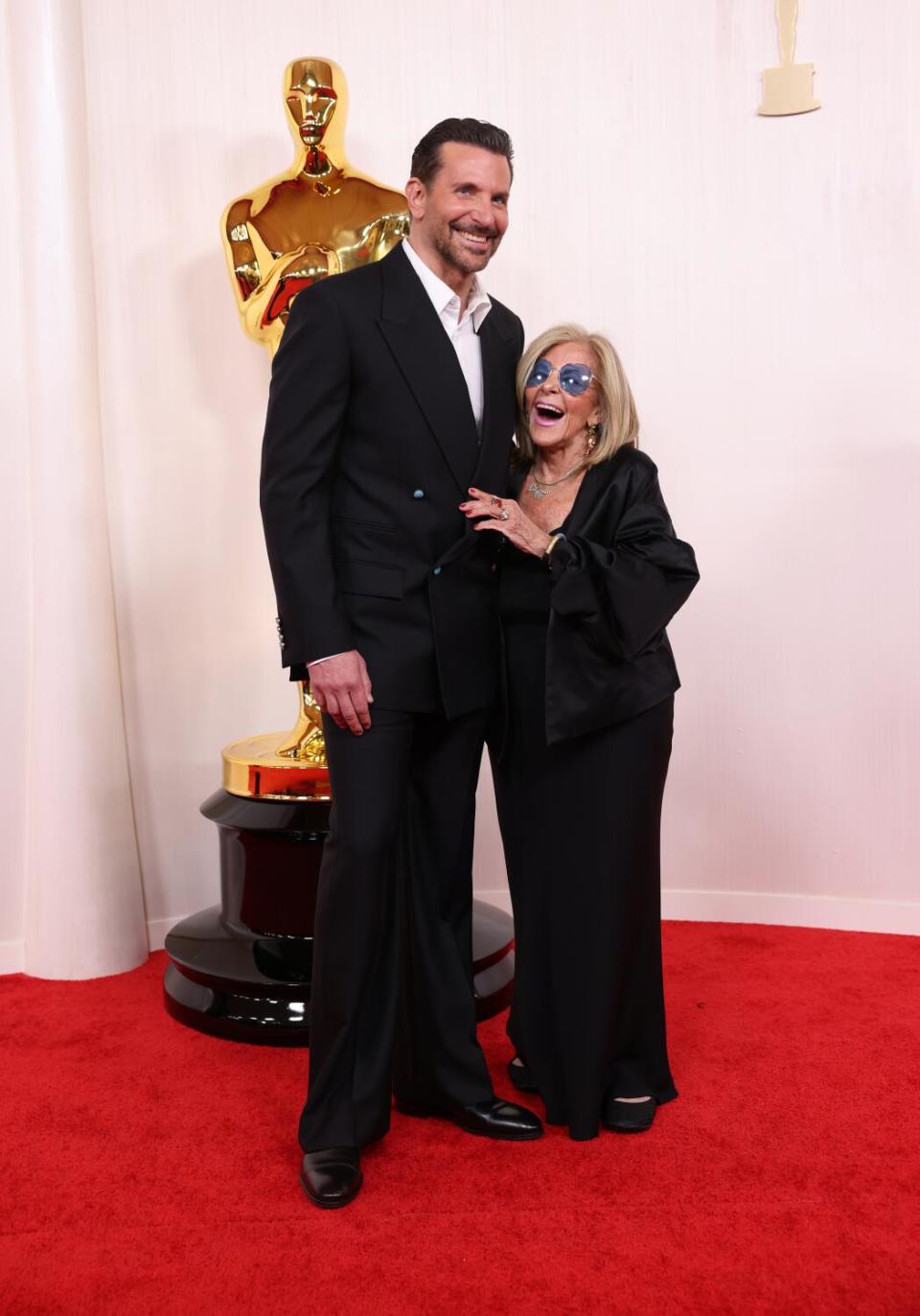 Bradley Cooper and Gloria Campano laugh on the red carpet.