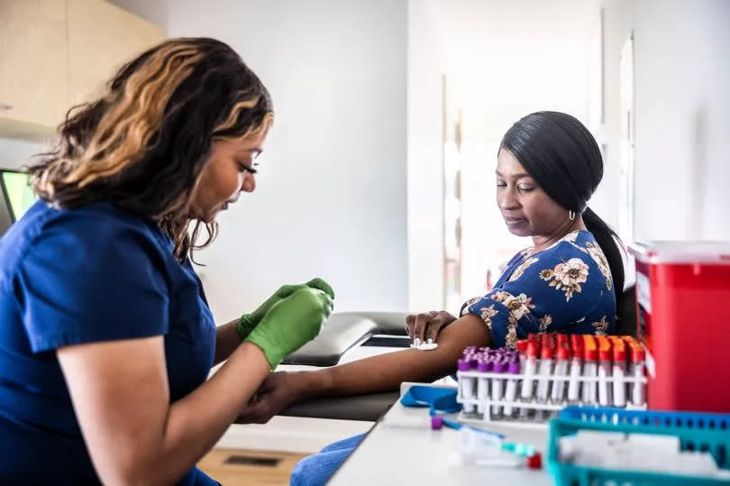 Female nurse drawing blood sample from woman in medical office