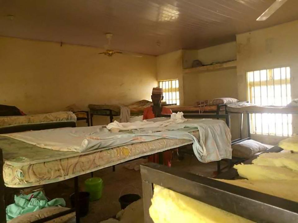 <p>A man stands in the deserted school dormitory after bandits invaded and took away over 300 schoolgirls in Jangede</p> (Reuters)