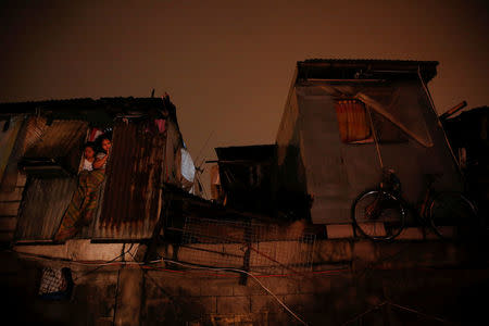 Residents of a slum in Parola look out from inside their house at the scene where a man identified to be on a drug watchlist was killed in a shooting encounter with police in Manila, Philippines early October 11, 2016. REUTERS/Damir Sagolj/File Photo