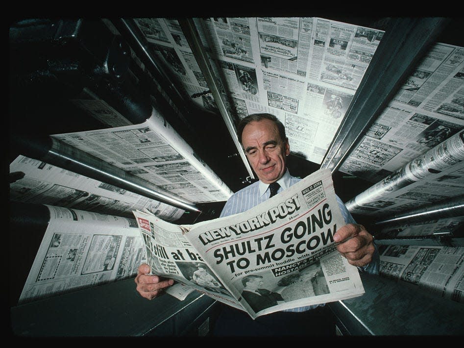 Publishing magnate Rupert Murdoch at the printing presses of the New York Post. He is reading a copy of the newspaper, whose headline declares "Schultz Going to Moscow".