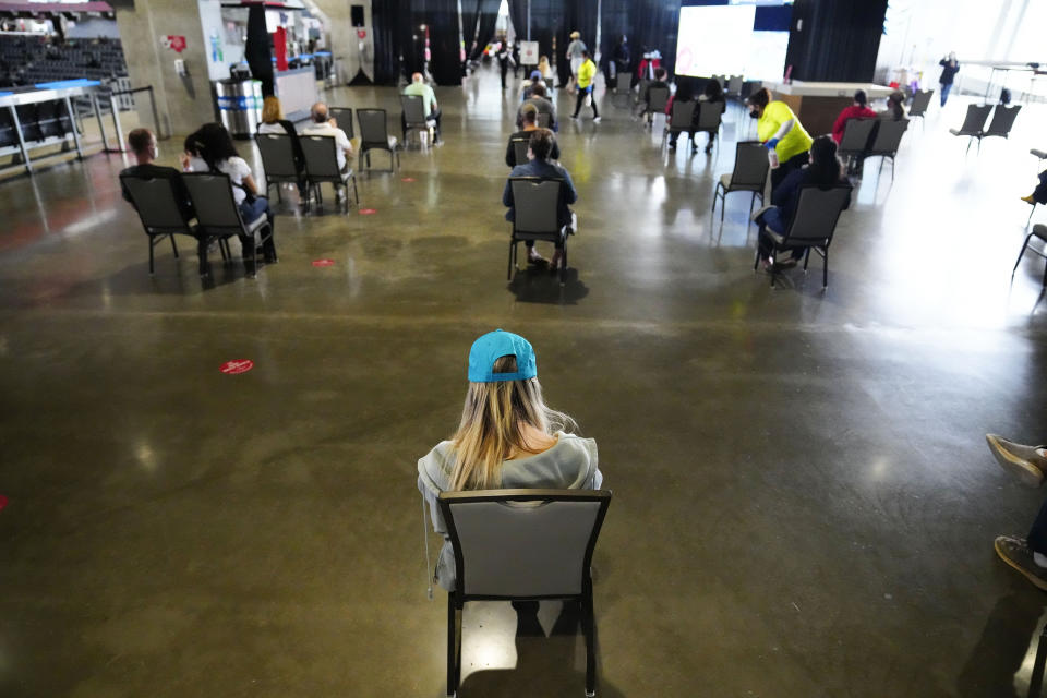 FILE - In this March 25, 2021, file photo, people wait to receive a vaccine at Mercedes-Benz Stadium in Atlanta. A new poll from The Associated Press-NORC Center for Public Affairs Research shows that the percentage of Americans resisting getting inoculated has shrunk in the past few months. But it’s still not enough to pull America out of the pandemic, and reach herd immunity. (AP Photo/Brynn Anderson, File)