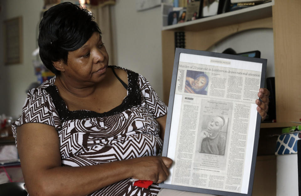 In this photo taken Tuesday, Aug. 6, 2019 Brenda Scurlock is shown in her home in Lumber Bridge, N.C. holding a newspaper clipping about her son's murder. Scurlock's son Avery Scurlock, who used the name Chanel when dressing as a woman in social settings and hoped to have sex reassignment surgery, was found shot to death in June. This death of a transgender person in North Carolina is one of 18 so far this year, and 17 of the victims have been black women. (AP Photo/Gerry Broome)