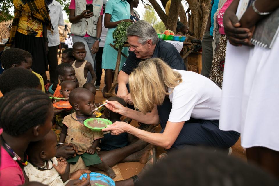 Relief Society General President Camille N. Johnson and Elder Ian S. Ardern of the Africa Central Area Presidency feed children with food provided by UNICEF and The Church of Jesus Christ of Latter-day Saints in northeastern Uganda in March 2023. | The Church of Jesus Christ of Latter-day Saints