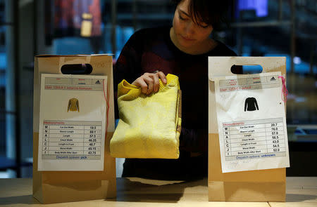 A staff member packs a knitted sweater into a customer pick up bag at the Adidas Knit for You store in Berlin, Germany March 7, 2017. REUTERS/Fabrizio Bensch