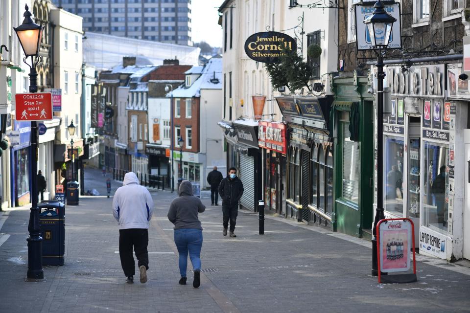 Pedestrians walk along a high street with the shops closed in Maidstone, southeast England, on February 12, 2021 as life continues in Britain's third coronavirus lockdown that has closed all non-essential stores in an effort to suppress Covid-19 infections. - Britain's economy shrank by a record 9.9 percent last year on the fallout from the coronavirus, official data showed on February 12, but a rapid vaccines rollout has boosted the outlook. (Photo by Ben STANSALL / AFP) (Photo by BEN STANSALL/AFP via Getty Images)