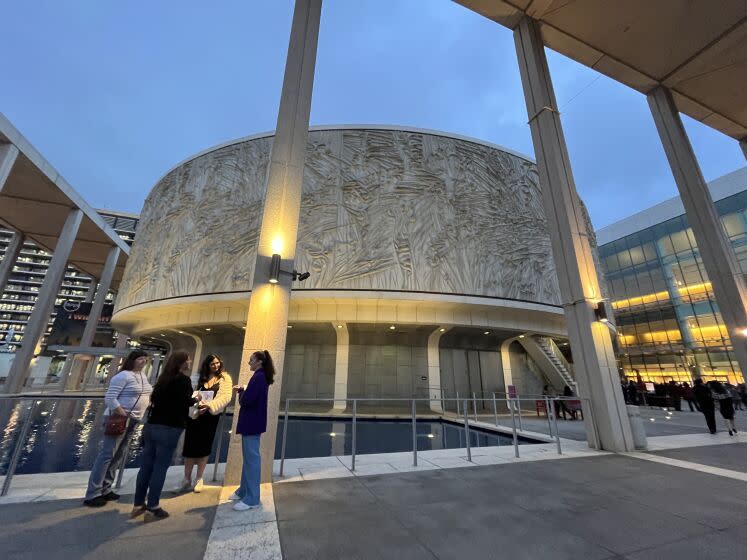 Two women hand leaflets to two theatergoers before the circular architecture of the Mark Taper Forum