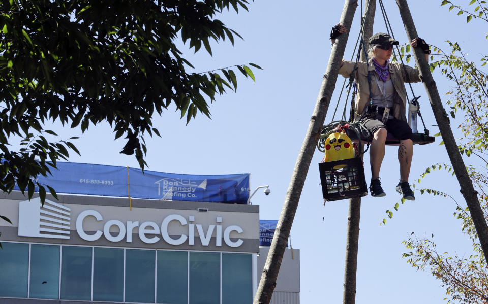 Julie Henry sits on a suspended platform as she protests outside the headquarters of CoreCivic Monday, Aug. 6, 2018, in Nashville, Tenn. The Tennessee-based company is one of the nation's largest private prison operators and also runs eight immigration detention centers for Immigration and Customs Enforcement. (AP Photo/Mark Humphrey)