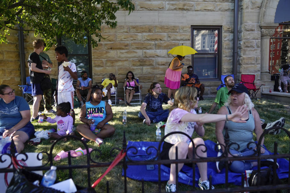 People gather in the shade at the scene where an apartment building partially collapsed two days earlier, Tuesday, May 30, 2023, in Davenport, Iowa. Five residents of the six-story apartment building remained unaccounted for and authorities feared at least two of them might be stuck inside rubble that was too dangerous to search. (AP Photo/Erin Hooley)