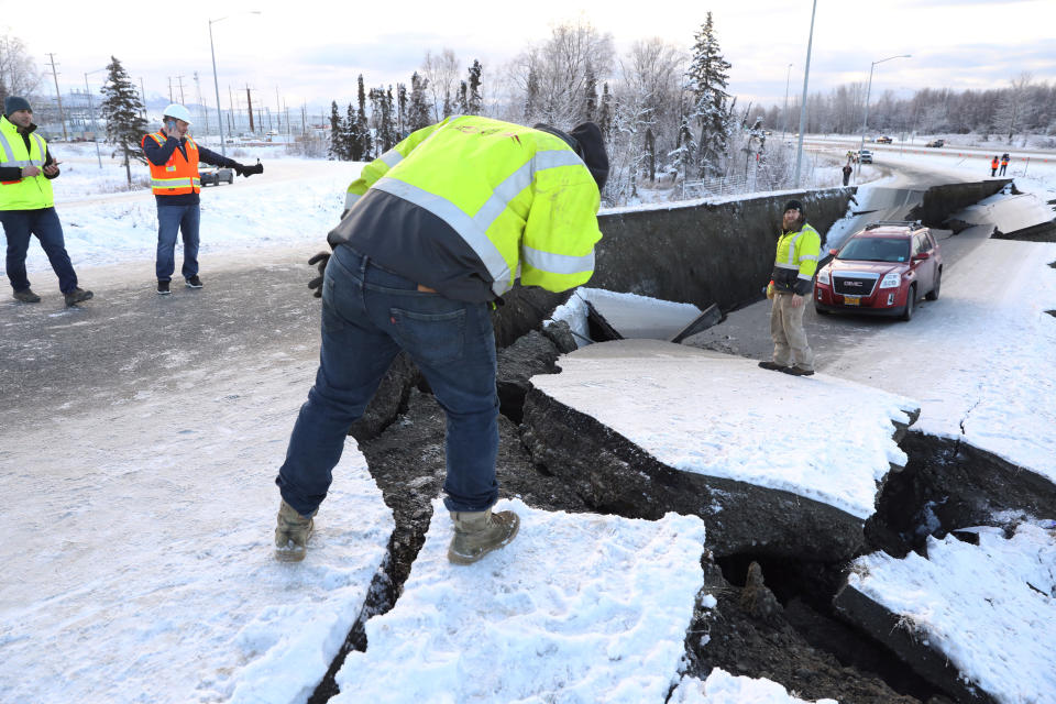 Workers check the damage along that roadway near the airport in Anchorage.