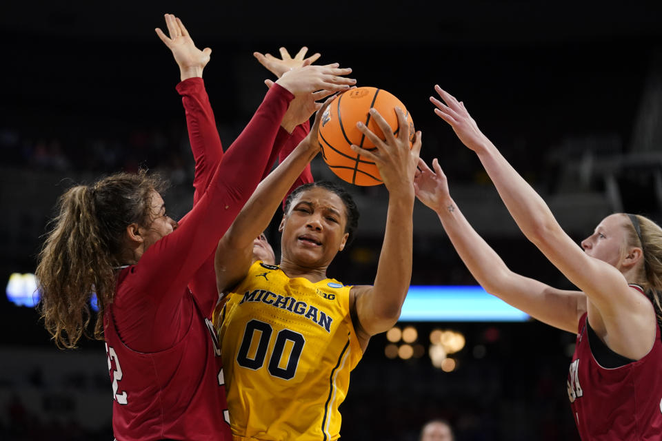 Michigan's Naz Hillmon (00) fights her way to the basket as South Dakota's Kyah Watson, left, and Grace Larkins defend during the second half of a college basketball game in the Sweet 16 round of the NCAA women's tournament Saturday, March 26, 2022, in Wichita, Kan. (AP Photo/Jeff Roberson)