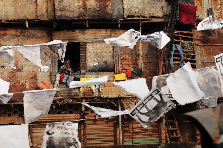 A Bangladesh resident of a shanty town looks out of a window on to a street filled with political posters in Dhaka on January 3, 2014