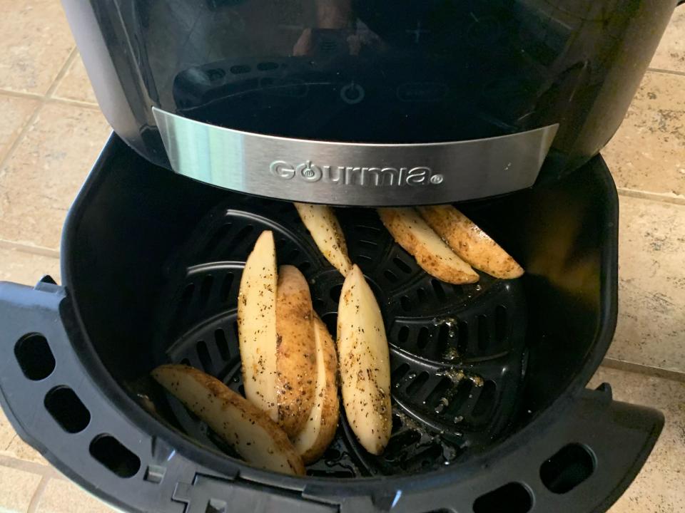 The seasoned, uncooked potato wedges in the air fryer basket