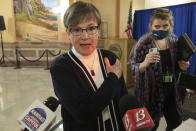 Kansas Gov. Laura Kelly gestures to the spot on her left arm where she received a COVID-19 vaccine shot as she tells reporters she had no reaction to it, Monday, Jan. 4, 2021, at the Statehouse in Topeka, Kan. Kelly says she is very comfortable with the distribution of vaccines across the state, saying federal data showing Kansas lagging behind all others in inoculations is the result of a lag in reporting. (AP Photo/John Hanna)