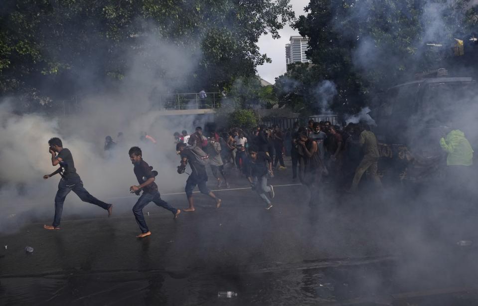 Students run for cover as police fire tear gas to disperse protesting members of the Inter University Students Federation during an anti government protest in Colombo, Sri Lanka, Thursday, May 19, 2022. Sri Lankans have been protesting for more than a month demanding the resignation of President Gotabaya Rajapaksa, holding him responsible for the country's worst economic crisis in recent memory. (AP Photo/Eranga Jayawardena)