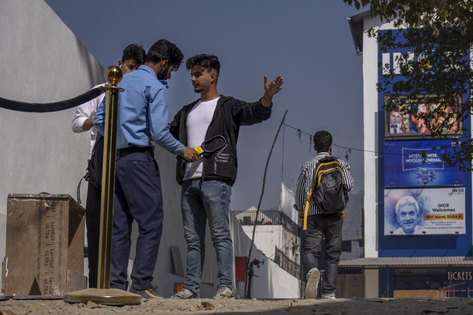 A security guard frisks a Kashmiri at the entrance of Kashmir's first multiplex cinema after it was opened to public for the first time in Srinagar, Indian controlled Kashmir, Saturday, Oct. 1, 2022. The multi-screen cinema hall has opened in the main city of Indian-controlled Kashmir for public for the first time in 14 years. The 520-seat hall with three screens opened on Saturday, Oct. 1, amid elaborate security but only about a dozen viewers lined up for the first morning show. (AP Photo/Dar Yasin)