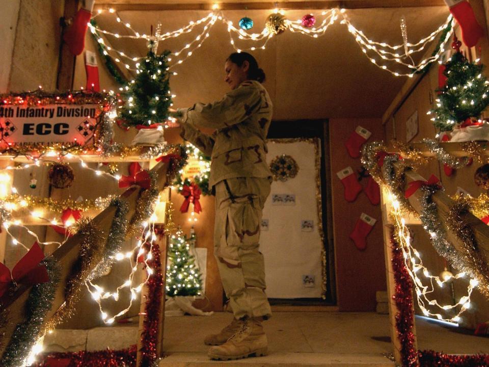Specialist Hernandez Lorie from the 4th Infantry Division of the US army sets lights on a Christmas decoration at her base in Tikrit, 180 Kilometers (110 miles) north of the Iraqi capital Baghdad, 23 December 2003.