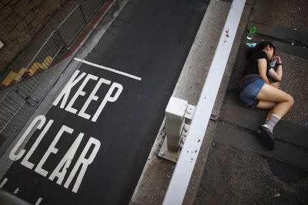 A protester sleeps as she blocks a street near government headquarters in Hong Kong September 30, 2014. REUTERS/Carlos Barria