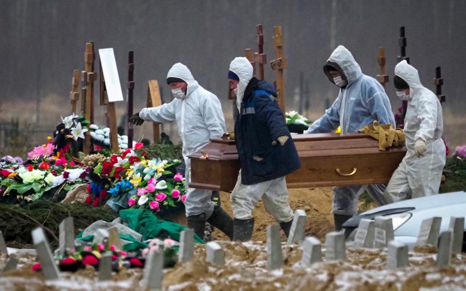 Grave diggers wearing protective suits carry the coffin of a COVID-19 victim in the section of a cemetery reserved for coronavirus victims in Kolpino, outside St.Petersburg, Russia - Dmitri Lovetsky /AP