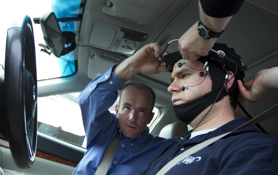 Russ Martin of triple A, is assisted by Joel Cooper, left, hooking the electroencephalographic (EEG)-configured skull cap to the research vehicle during a demonstrations in support of their new study on distracted driving in Landover, Md., Tuesday, June 11, 2013. (AP Photo/Manuel Balce Ceneta)