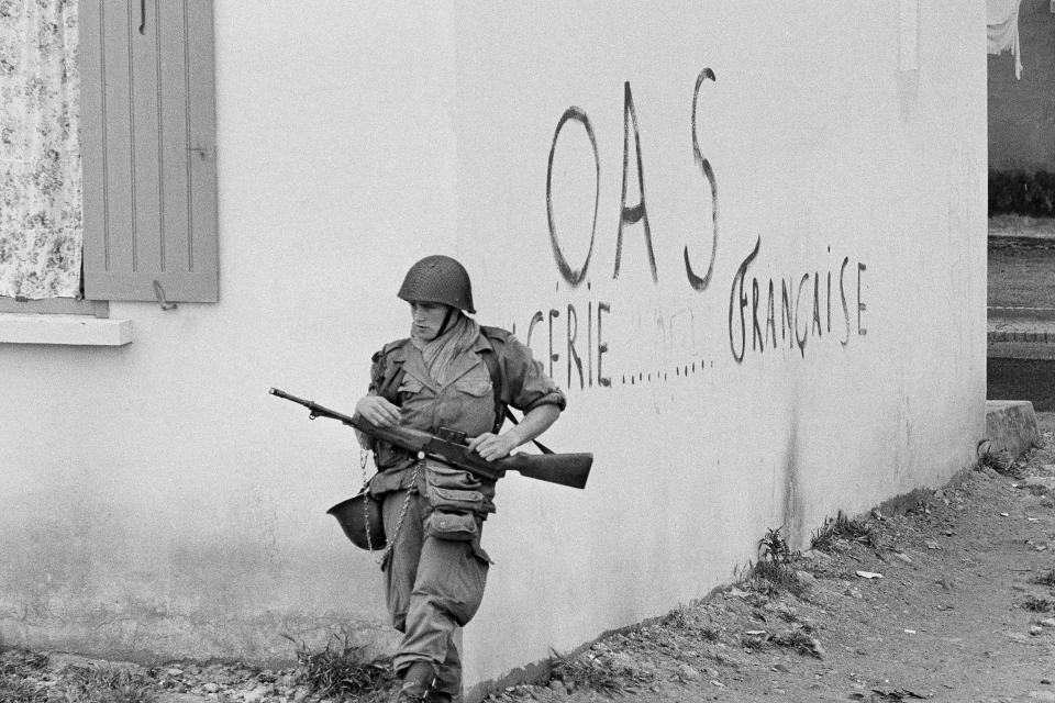 FILE - A soldier of the French army is shown in position at the corner of a building in the St. Eugene district of Oran in Algeria, April 28, 1962. Algeria is celebrating 60 years of independence from France on Tuesday July 5, 2022 with nationwide ceremonies, a pardon of 14,000 prisoners and its first military parade in years. Tuesday's events mark 60 years since the official declaration of independence on July 5, 1962, after a brutal seven-year war which ended 132 years of colonial rule. The war, which killed at least 1.5 million people, remains a point of tension in relations between Algeria and France. OAS (Organization of the Secret Army) French dissident graffiti reads "Algeria French". (AP Photo/Horst Faas, File)