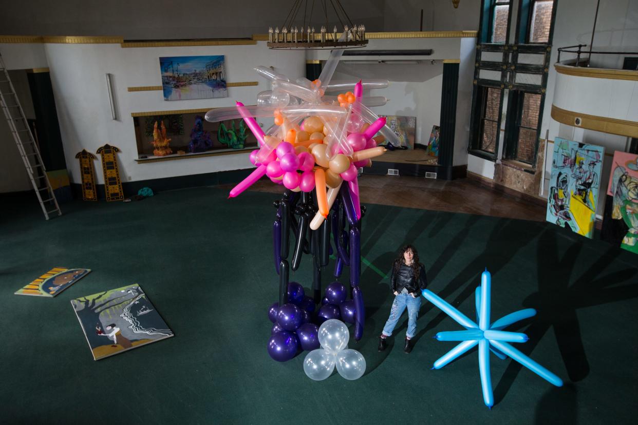 Painter and muralist Jenny Mathews poses for a portrait inside The Milk House at Pioneer Hall Wednesday, April 21, 2021, in Rockford, surrounded by Melinda Cook's balloon sculptures. This year's ArtScene will be held Friday and Saturday.