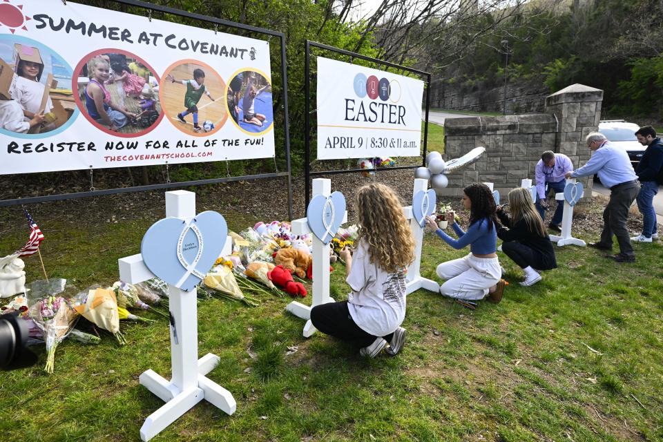 Girls write messages on crosses at an entry to Covenant School, Tuesday, March 28, 2023, in Nashville, Tenn., which has become a memorial for the victims of Monday's school shooting. (AP Photo/John Amis)