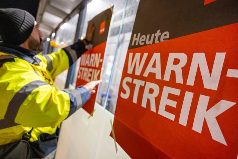 Strikers stick posters with the words "Warning strike today" on a window at the staff entrance of Cologne Bonn Airport, one of 11 major German airports that have started a one-day strike. Thomas Banneyer/dpa