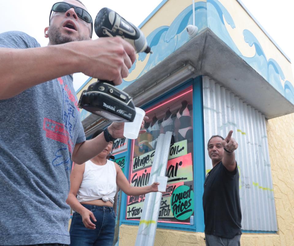 Workers at the Lazy Gator Gift Shop in Daytona Beach begin to board up on Tuesday, Sept. 27, 2022.