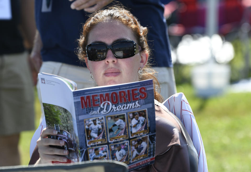 Roy Halladay fan Jacqueline Sarricchio of Bellmar, N.J., reads a program while waiting for the start of the National Baseball Hall of Fame induction ceremony at the Clark Sports Center on Sunday, July 21, 2019, in Cooperstown, N.Y. (AP Photo/Hans Pennink)