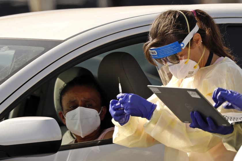 INGLEWOOD, CA - JANUARY 19: Staff and volunteers distribute the COVID-19 vaccine to people as they remain in their vehicles at The Forum in Inglewood. The Forum is one of five mass-vaccination sites that opened Tuesday in Los Angeles county. Todays inoculations were only available to front line health care workers and residents and staff of skilled nursing facilities and other long-term care facilities. Inoculations for the members of the eligible tier were administered from 10 a.m. to 4:30 p.m. Los Angeles County residents may find out when they are eligible to be vaccinated by visiting vaccinatelacounty.com, which is the county's vaccination website. The Forum on Tuesday, Jan. 19, 2021 in Inglewood, CA. (Al Seib / Los Angeles Times)