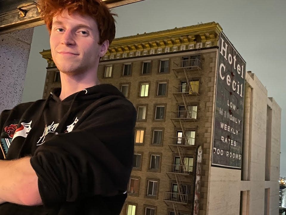 Peet standing in front of a window overlooking the Cecil Hotel.