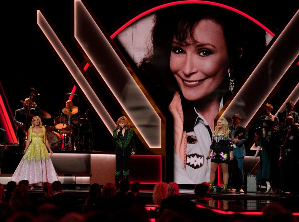 Carrie Underwood, from left, Reba McEntire and Miranda Lambert perform a tribute to the late singer Loretta Lynn, pictured on screen, during the 56th Annual CMA Awards on Wednesday, Nov. 9, 2022, at the Bridgestone Arena in Nashville, Tenn. (AP Photo/Mark Humphrey)