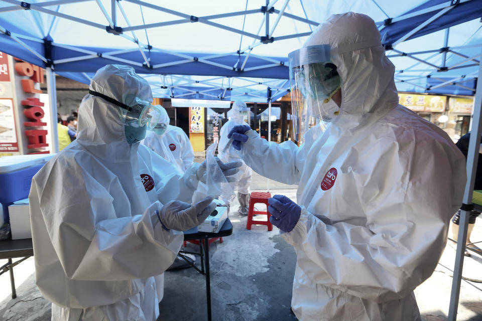 A health official wearing protective gears puts a sample of a person into a plastic bag during the COVID-19 testing at a makeshift clinic in Seoul, South Korea, Friday, June 5, 2020. (AP Photo/Ahn Young-joon)