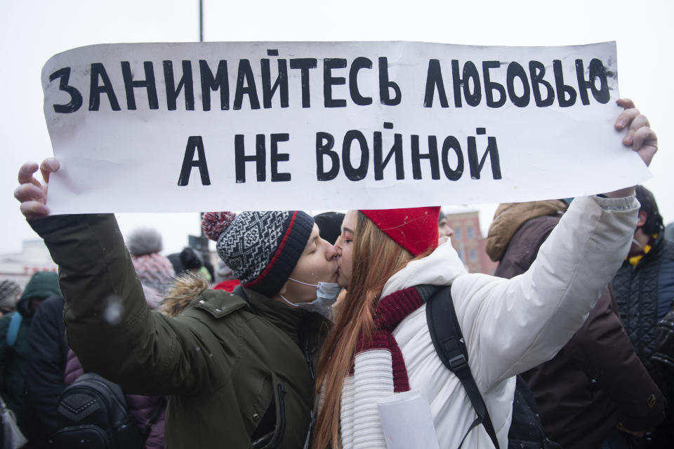 Young demonstrators kiss and hold a banner that reads: "Make love, Not war", during a protest against the jailing of opposition leader Alexei Navalny in Moscow, Russia, on Sunday, Jan. 31, 2021. Tens of thousands of people are protesting across Russia to demand the release of jailed opposition leader Alexei Navalny in wave of nationwide demonstrations that have rattled the Kremlin. Many chanted slogans against President Vladimir Putin. Activists say police detained more than 3,300 protesters across the country on Sunday, including over 900 in Moscow. (AP Photo/Denis Kaminev)