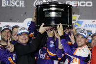 Denny Hamlin, right, celebrates as he and crew members hoist the championship trophy after winning the NASCAR Daytona 500 auto race at Daytona International Speedway, Monday, Feb. 17, 2020, in Daytona Beach, Fla. (AP Photo/Terry Renna)