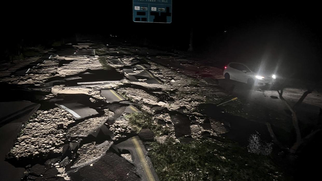 Broken-up pavement just before the Sanibel Causeway as a car drives by.