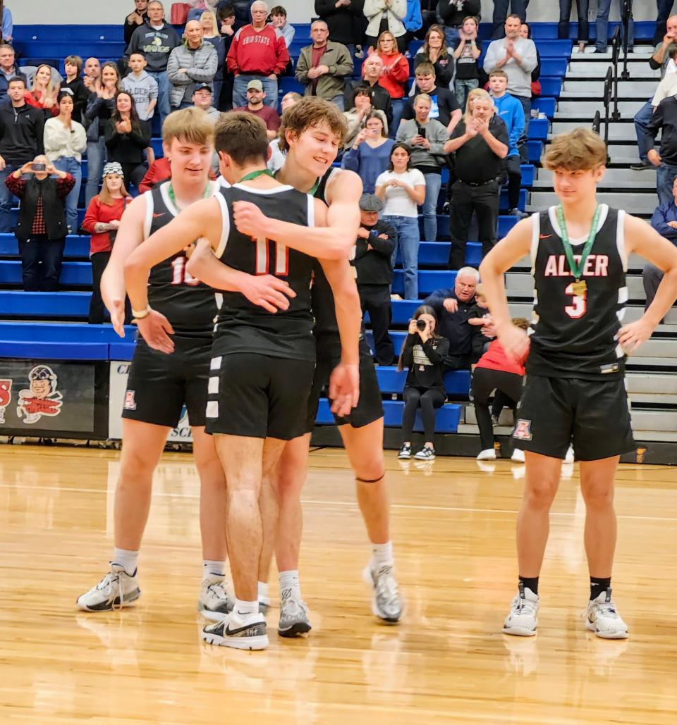 Jonathan Alder's Peyton Heiss hugs teammate Ryan Mark (11) after the Pioneers' 54-44 win over Watterson in a Division II district final Saturday at Central Crossing. Teammate Landon Dyer (10) is at left and Dylan Damron (3) is at right.