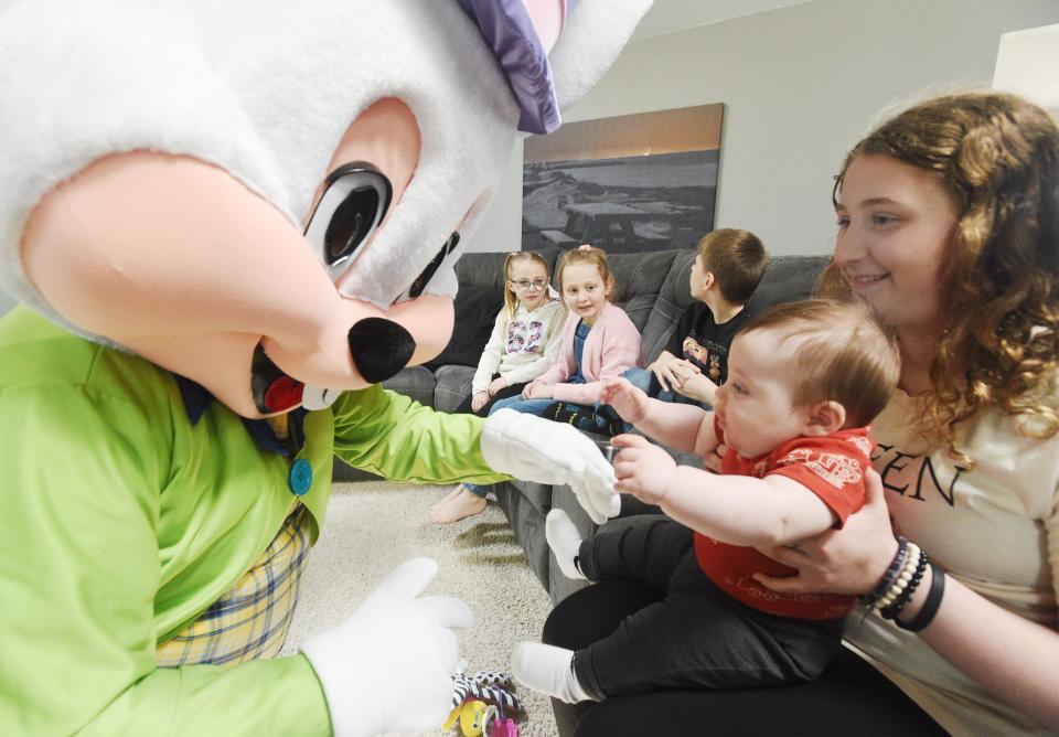 Joe Bell, left, portrays the Easter Bunny for a group of children, including Julian Czerpak, 7 months, and Veronica Adiutori, 11, right.