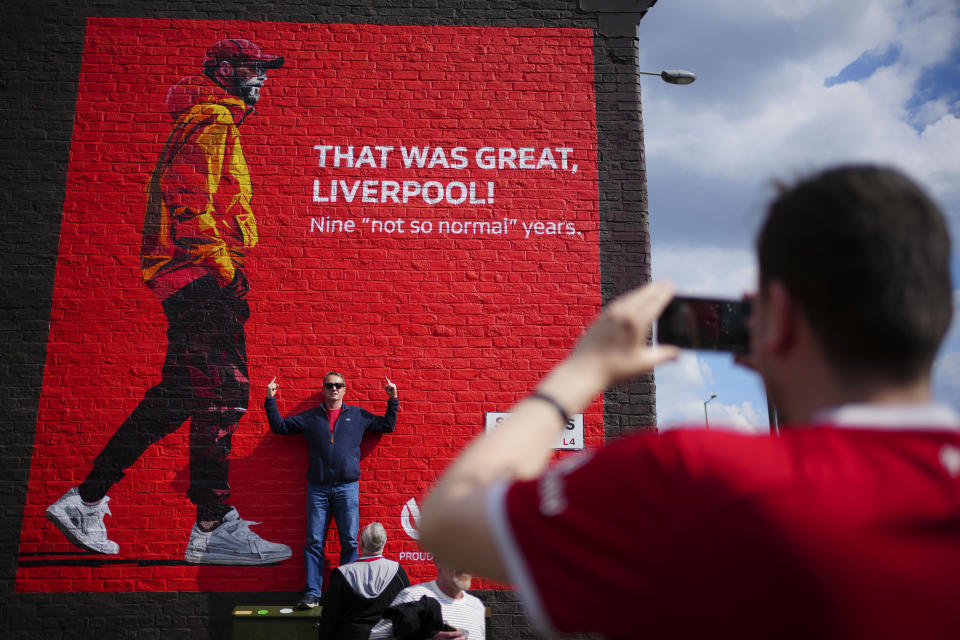 A fan poses for photos next to a mural with the image of Liverpool’s manager Jurgen Klopp prior to the English Premier League soccer match between Liverpool and Tottenham Hotspur at Anfield Stadium in Liverpool, England, Sunday, May 5, 2024. (AP Photo/Jon Super)