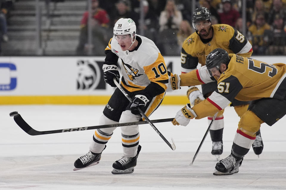 Vegas Golden Knights center Byron Froese (51) and Pittsburgh Penguins left wing Drew O'Connor (10) battle for the puck during the first period of an NHL hockey game Saturday, Jan. 20, 2024, in Las Vegas. (AP Photo/John Locher)