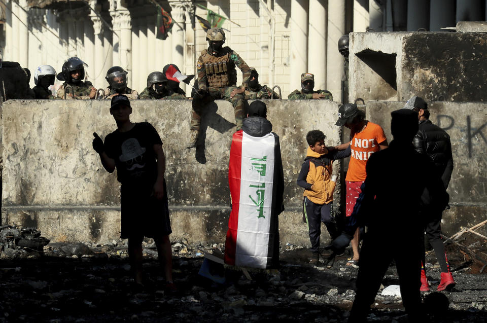 Iraqi security forces and anti-government protesters rest after both sides shake hands and converse in a rare moment of calm in hostilities called to allow time for rest after clashes in Baghdad, Iraq, Saturday, Nov. 30, 2019. (AP Photo/Hadi Mizban)