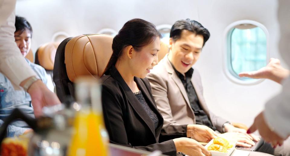 Passengers on a plane being served airline food. 