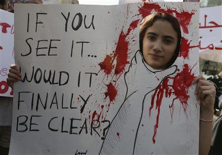 An activist holds a banner during a march against domestic violence against women, marking International Women's Day in Beirut March 8, 2014. REUTERS/Jamal Saidi