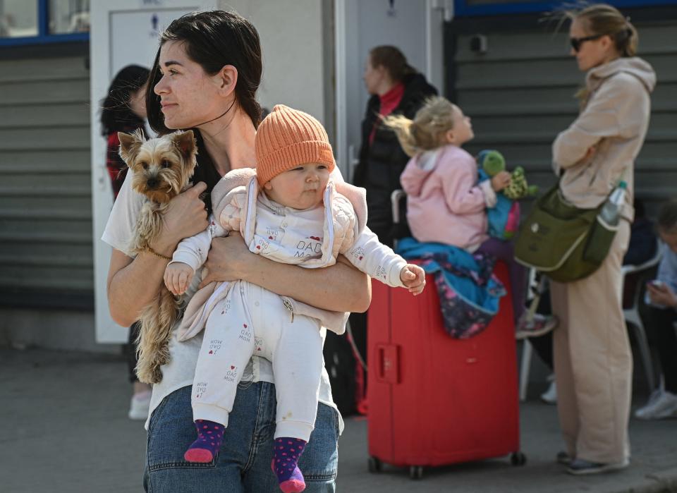 A Ukrainian refugee holds her baby and dog as she waits for a bus at a border crossing.