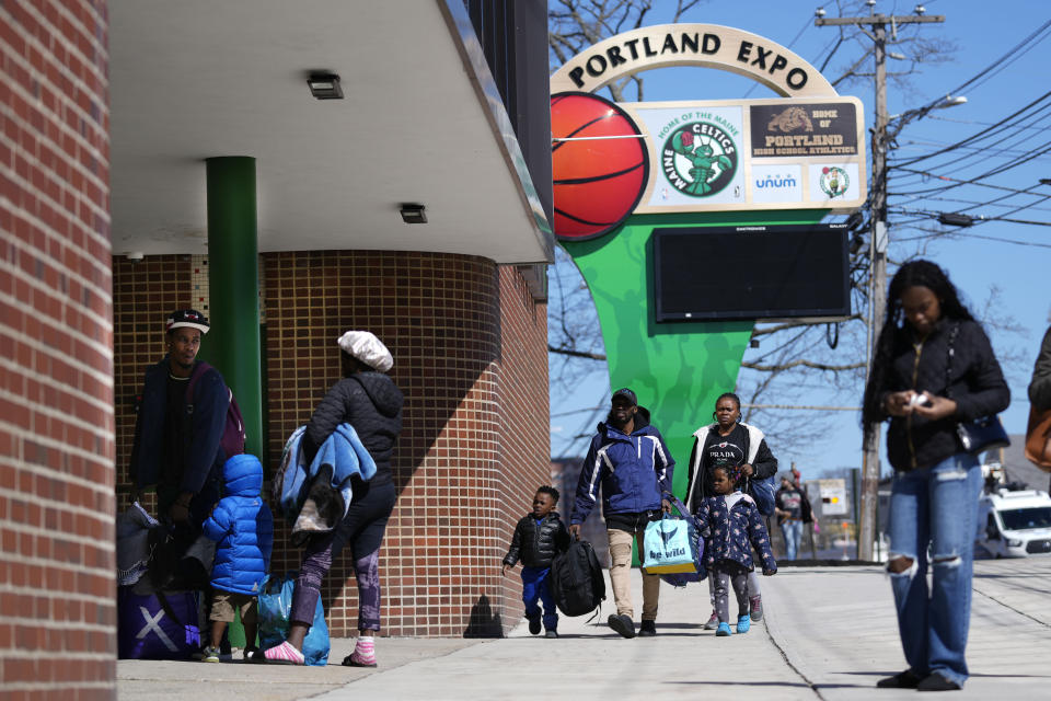 Asylum seekers arrive with their belongings at the Portland Expo Center, Monday, April 10, 2023, in Portland, Maine. The state is reopening a basketball arena for immigrants following the arrival of more than 800 asylums seekers since the beginning of the year. (AP Photo/Robert F. Bukaty)