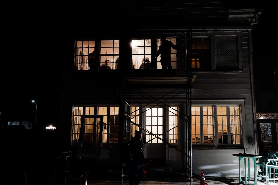 Crew members set up scaffolding outside to film through the window of the Manning home on the second floor.