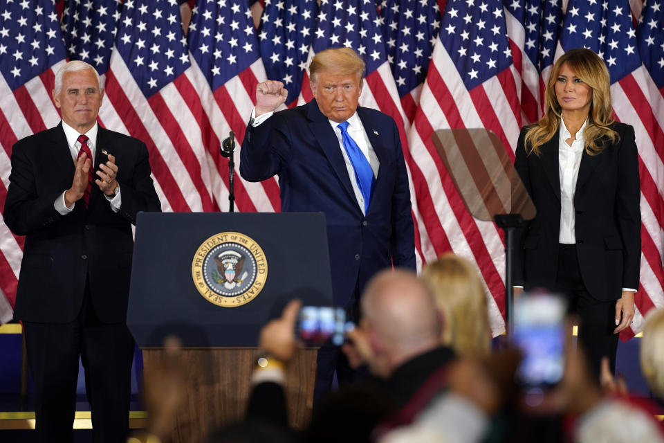 President Donald Trump pumps his fist after speaking in the East Room of the White House, early Wednesday, Nov. 4, 2020, in Washington, as Vice President Mike Pence and first lady Melania Trump watch. (AP Photo/Evan Vucci)